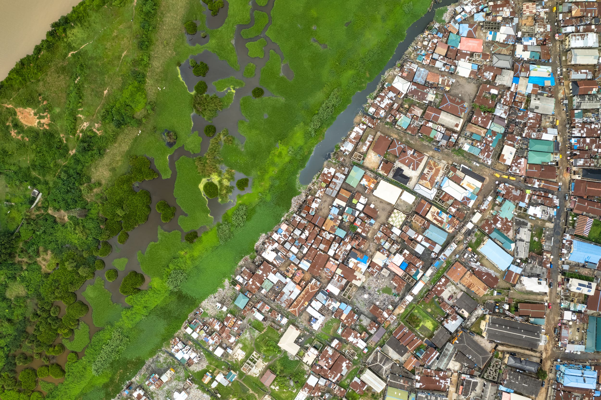 Aerial view of the built-up edge of Lagos meeting wetland along a channel of water